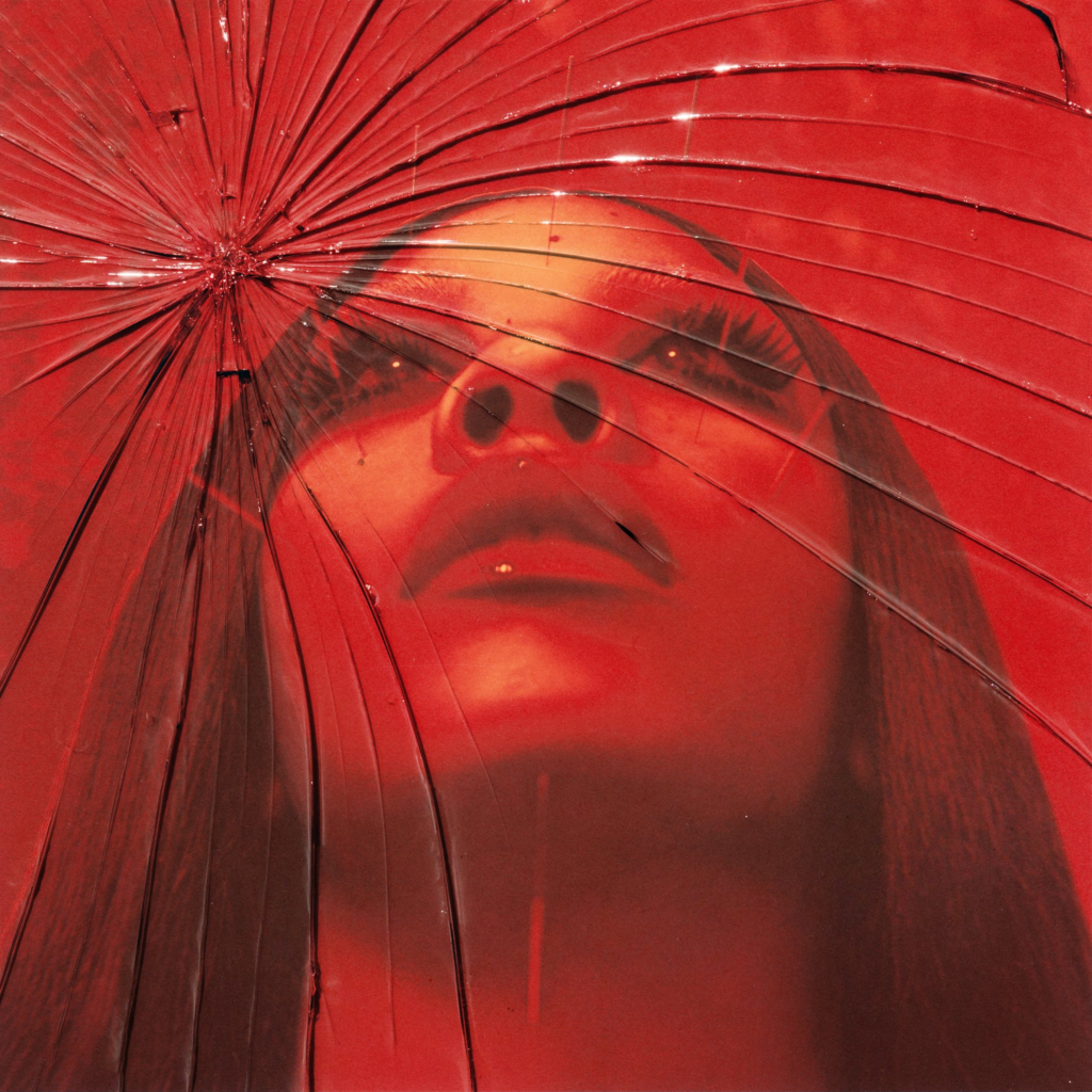 Album cover for Rico Nasty's Lethal: Deluxe. Shows Rico tilting her head up with a cracked glass effect with a red filter.