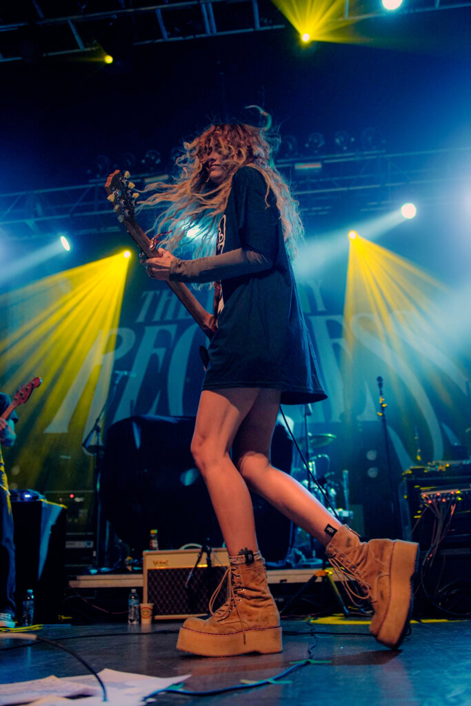 Image of Paris Jackson's left side as she is performing playing the guitar.